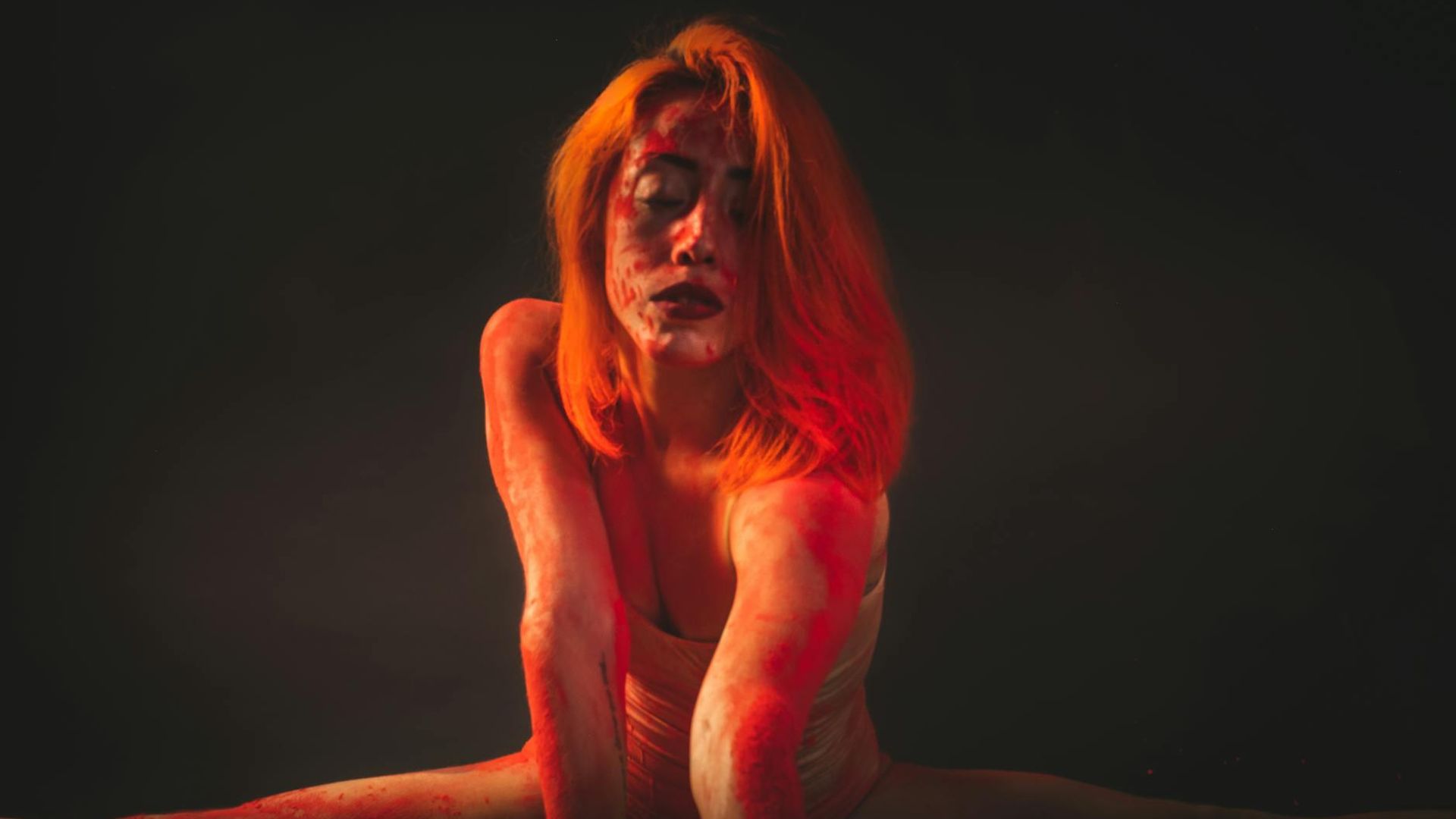 Athletic woman performing stretching exercises in a dark studio.